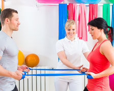 Physical therapists teaching a woman new exercises using elastic bands